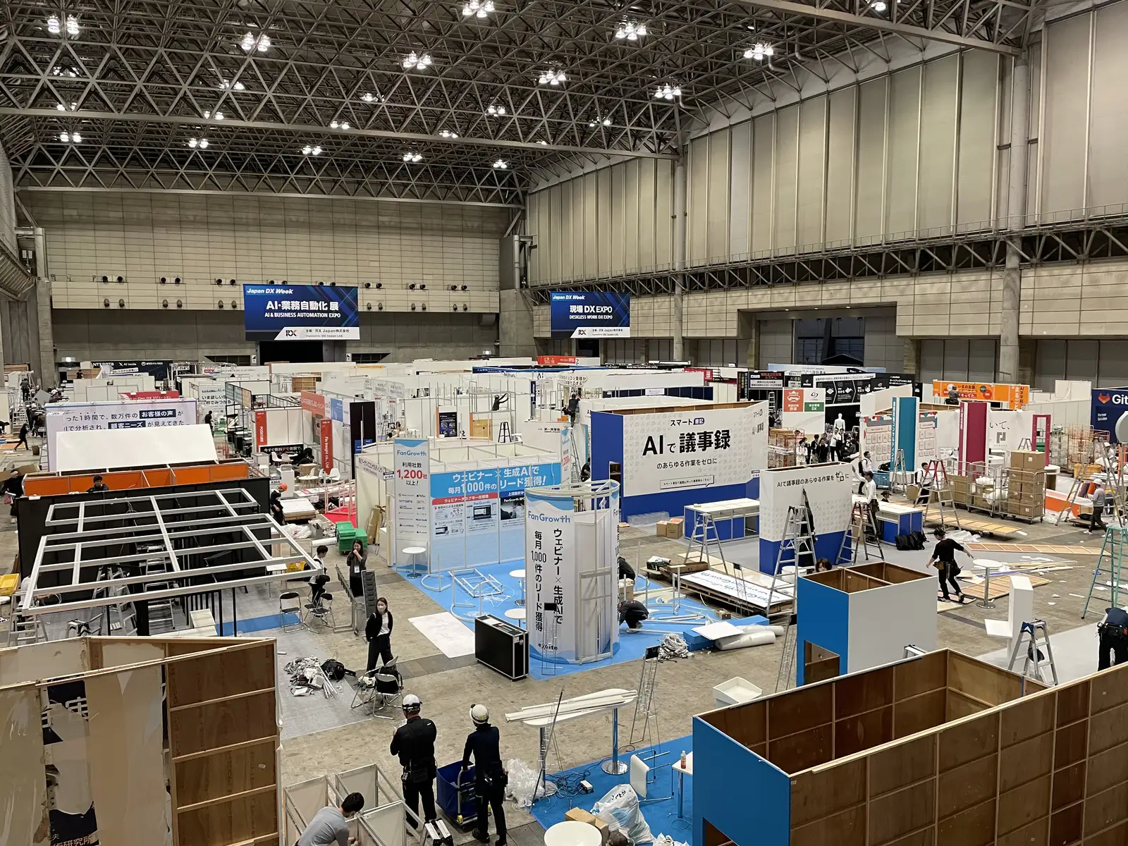 Exhibitor booths being packed up in a large exhibition hall at Japan IT Week, under AI and business automation expo banners
