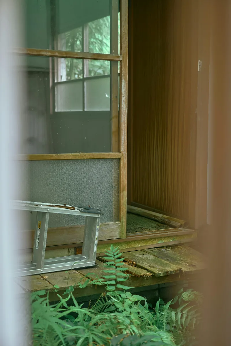 Rustic wooden porch with a broken screen door and ladder in Kamakura