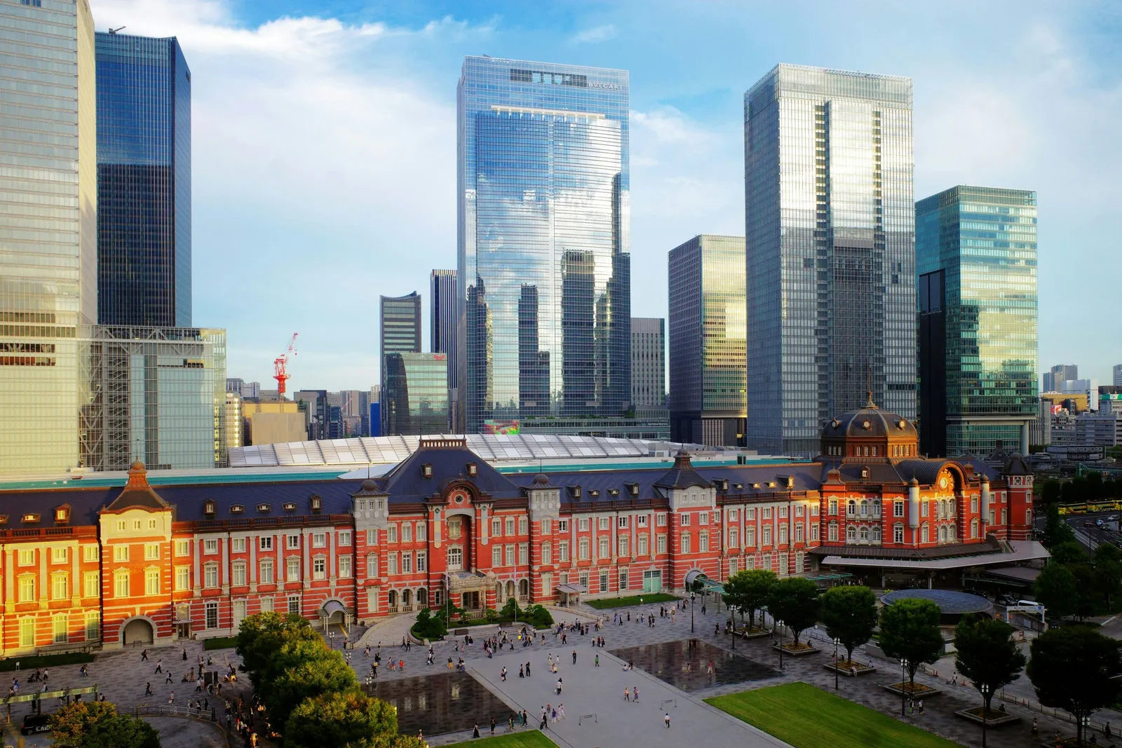 Glass office towers of Marunouchi rising behind the red brick Tokyo Station building and its plaza