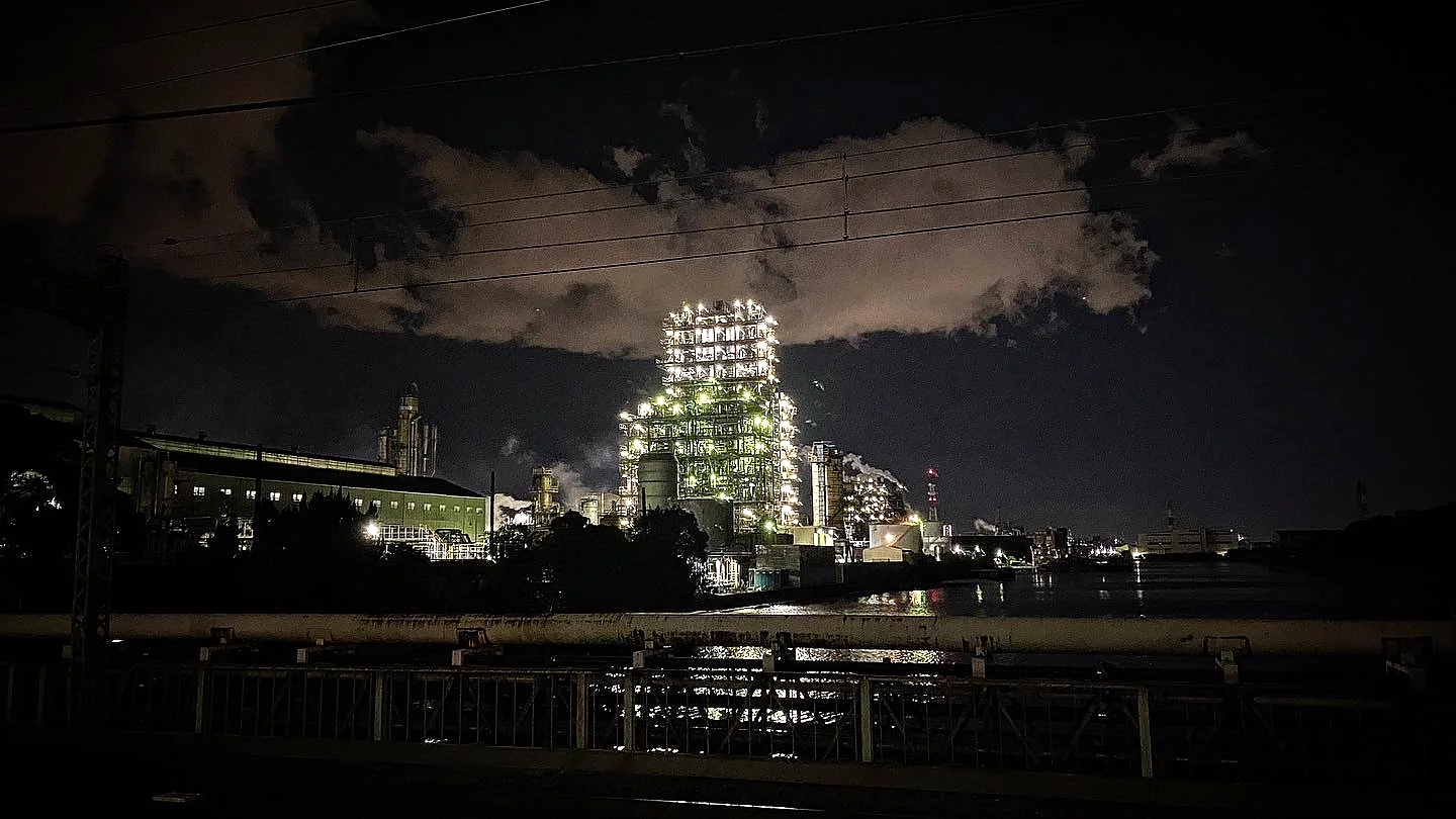 An illuminated industrial facility beside the water at night