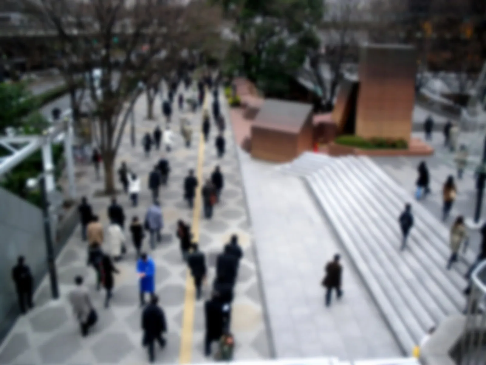 Office workers walking to work across a plaza in the Nishi-Shinjuku skyscraper district of Tokyo on a winter morning