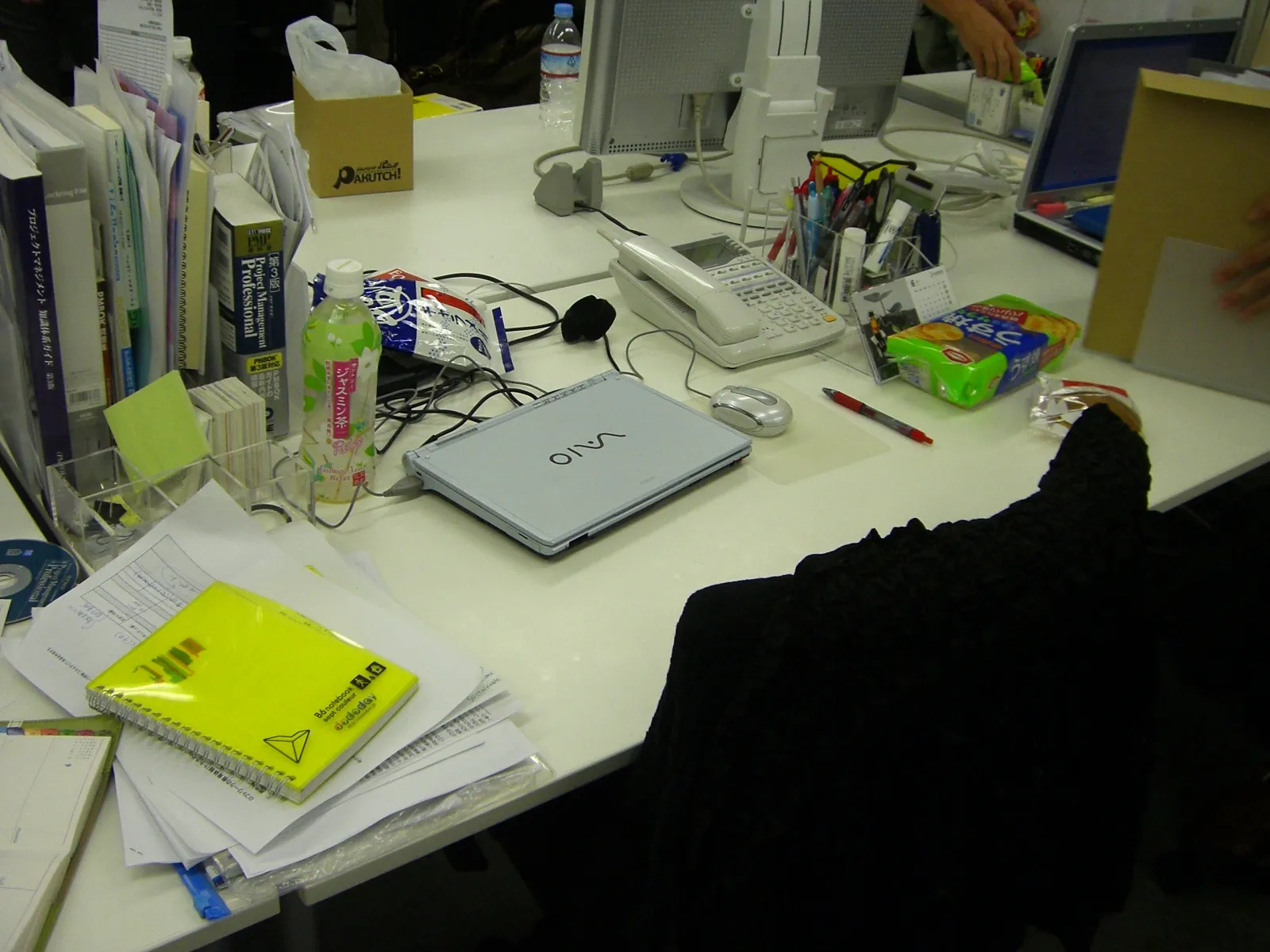 An office desk in Tokyo with a VAIO laptop, desk phone, paper files, notebooks and stationery