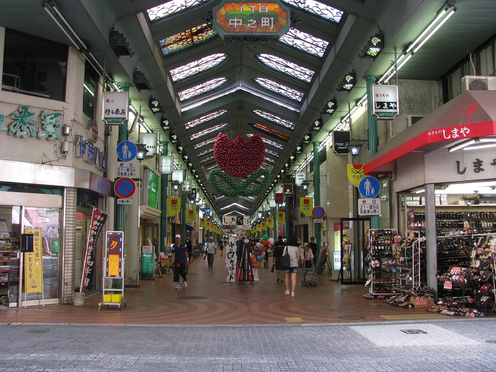 Shoppers walking through the covered Omotecho shopping arcade in central Okayama under a glass roof