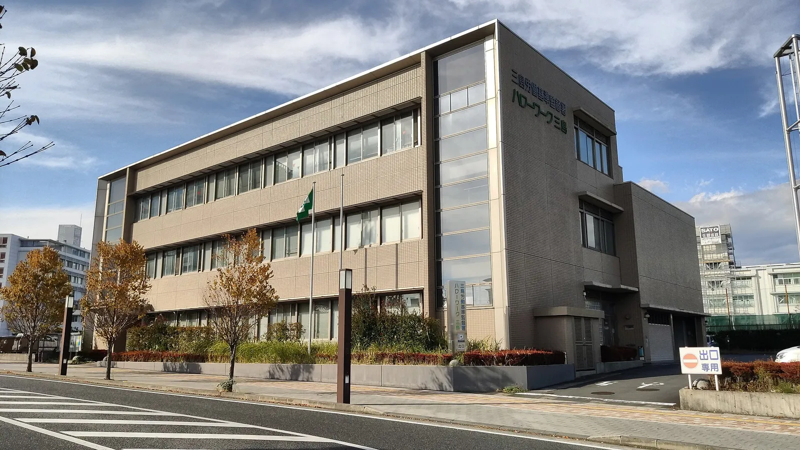 Exterior of the Hello Work Mishima public employment office, a four-storey building beside a road and crosswalk