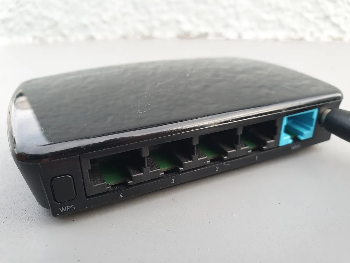 A small black office router with four network ports and a WPS button