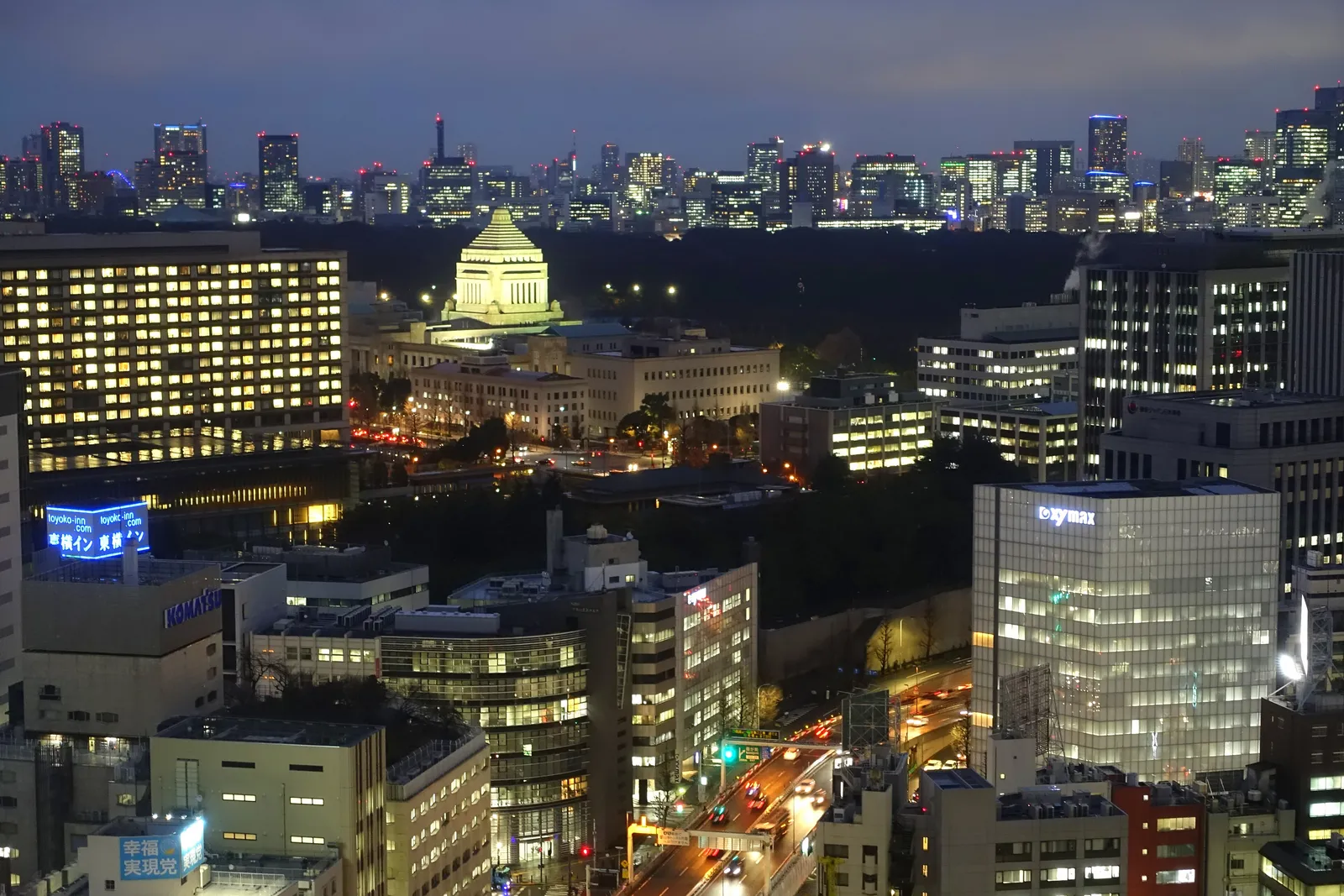 The National Diet Building lit up at night among office towers in central Tokyo, seen from above