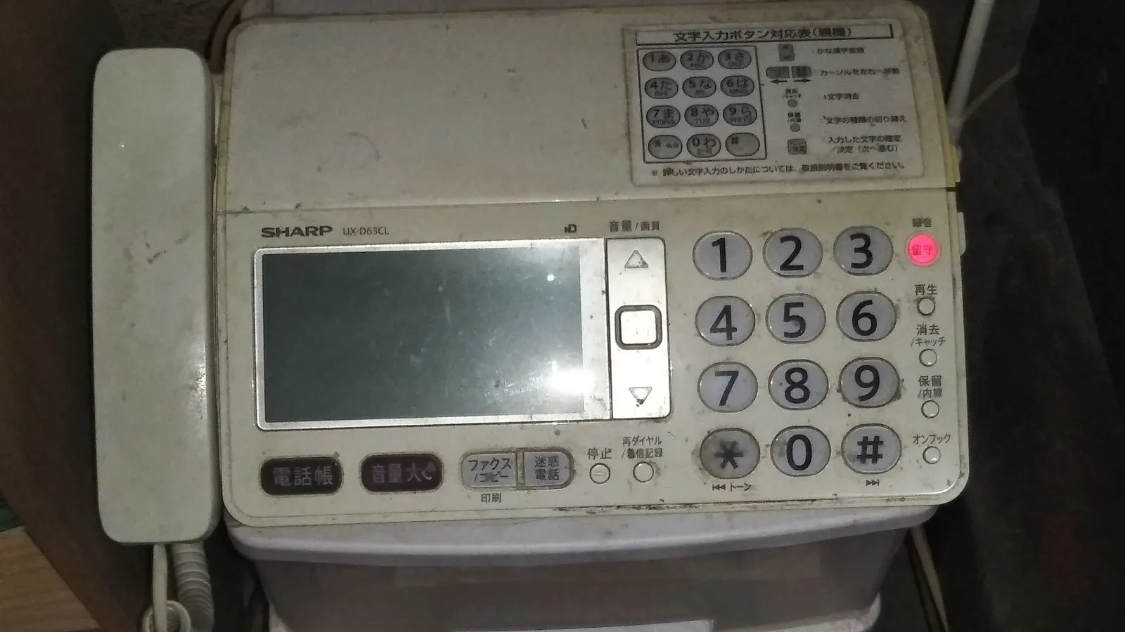 A white Sharp UX-D63CL fax and telephone unit with a handset, number keypad and Japanese button labels