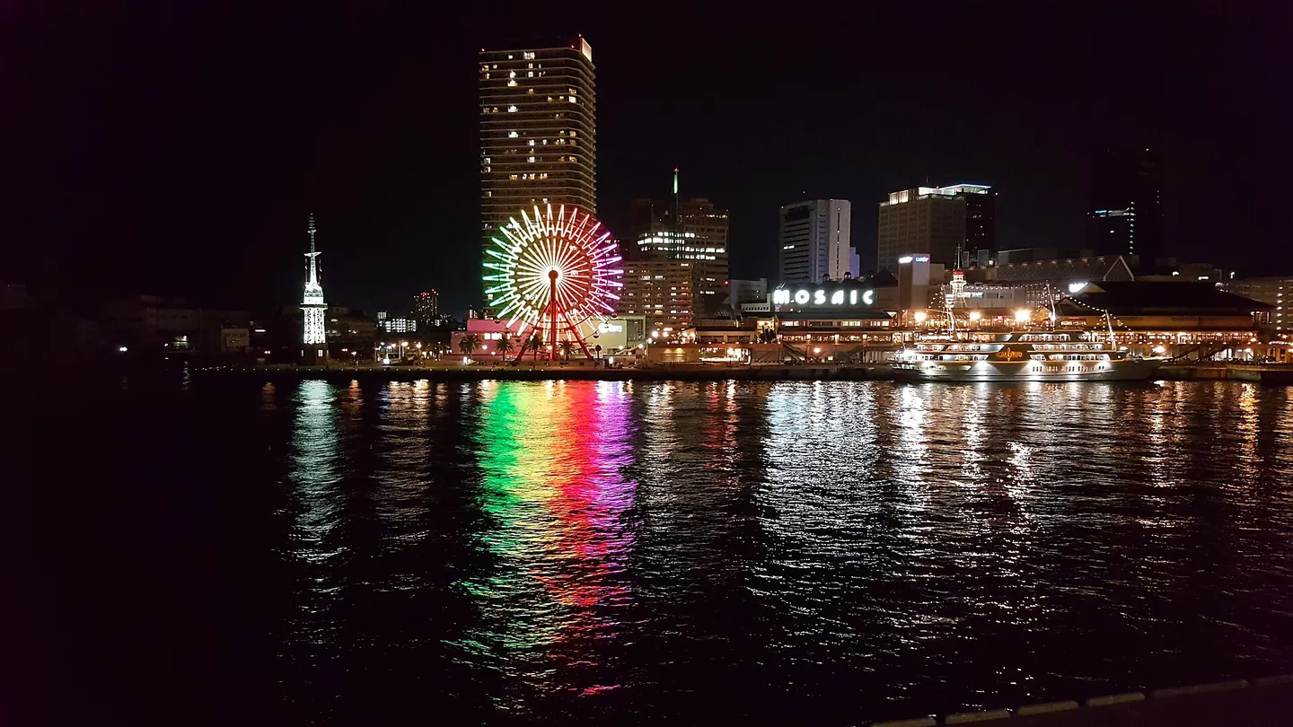 Kobe's Harborland waterfront at night, with a lit Ferris wheel and towers reflected in the harbor