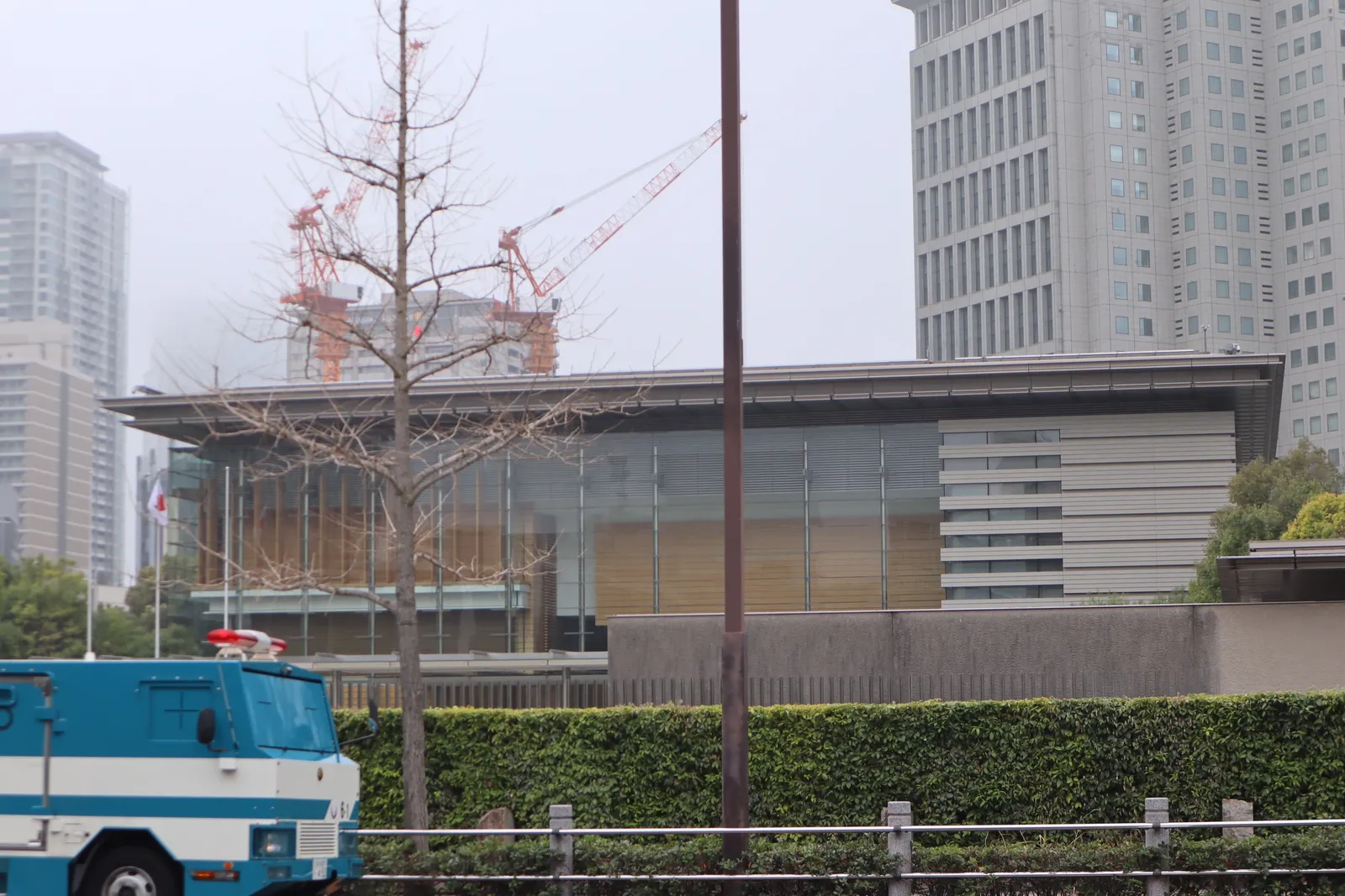 The Prime Minister's Official Residence in Nagatacho, Tokyo, behind a hedge with high-rise towers beyond