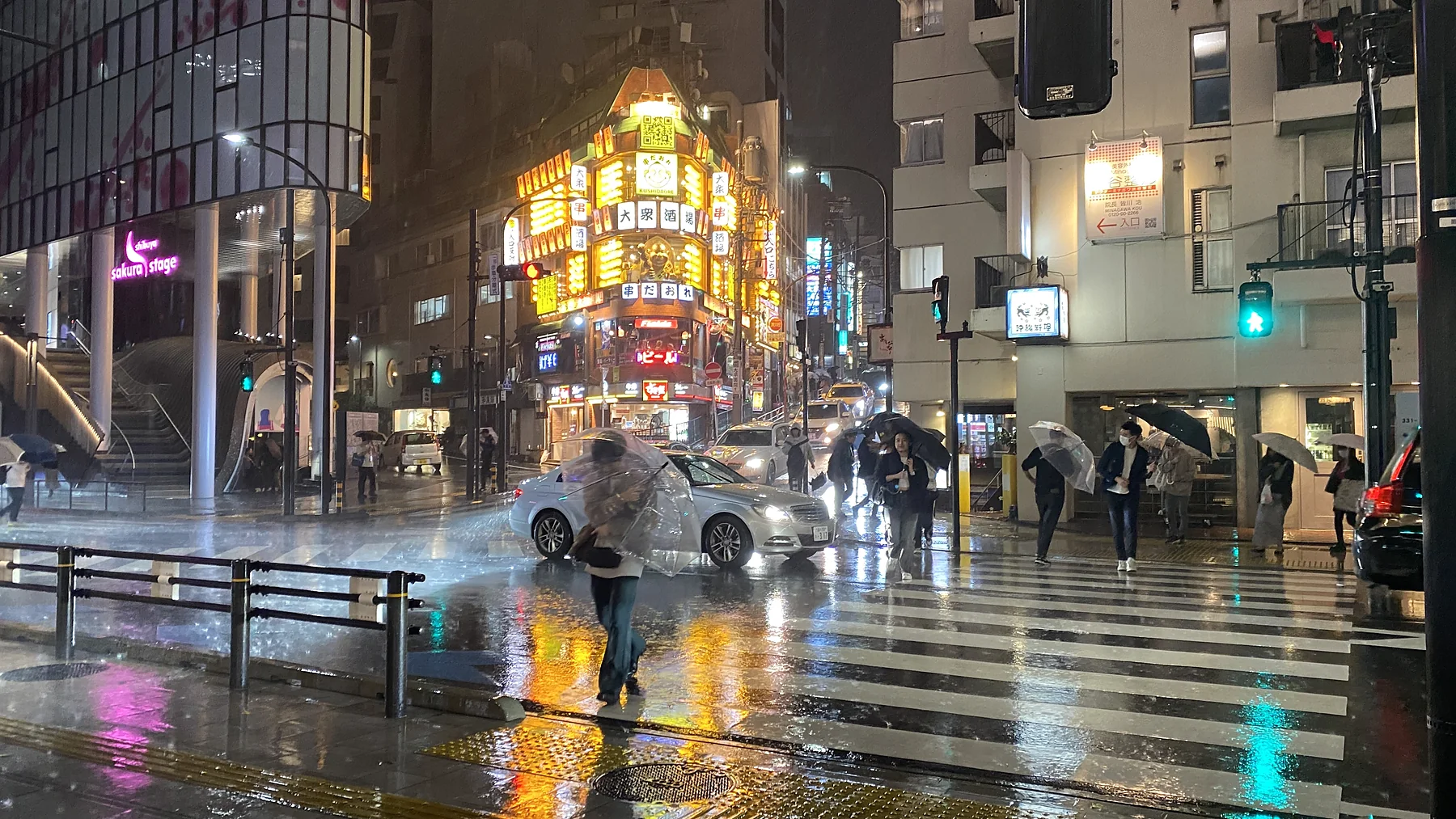 People crossing a rain-soaked city street in Japan