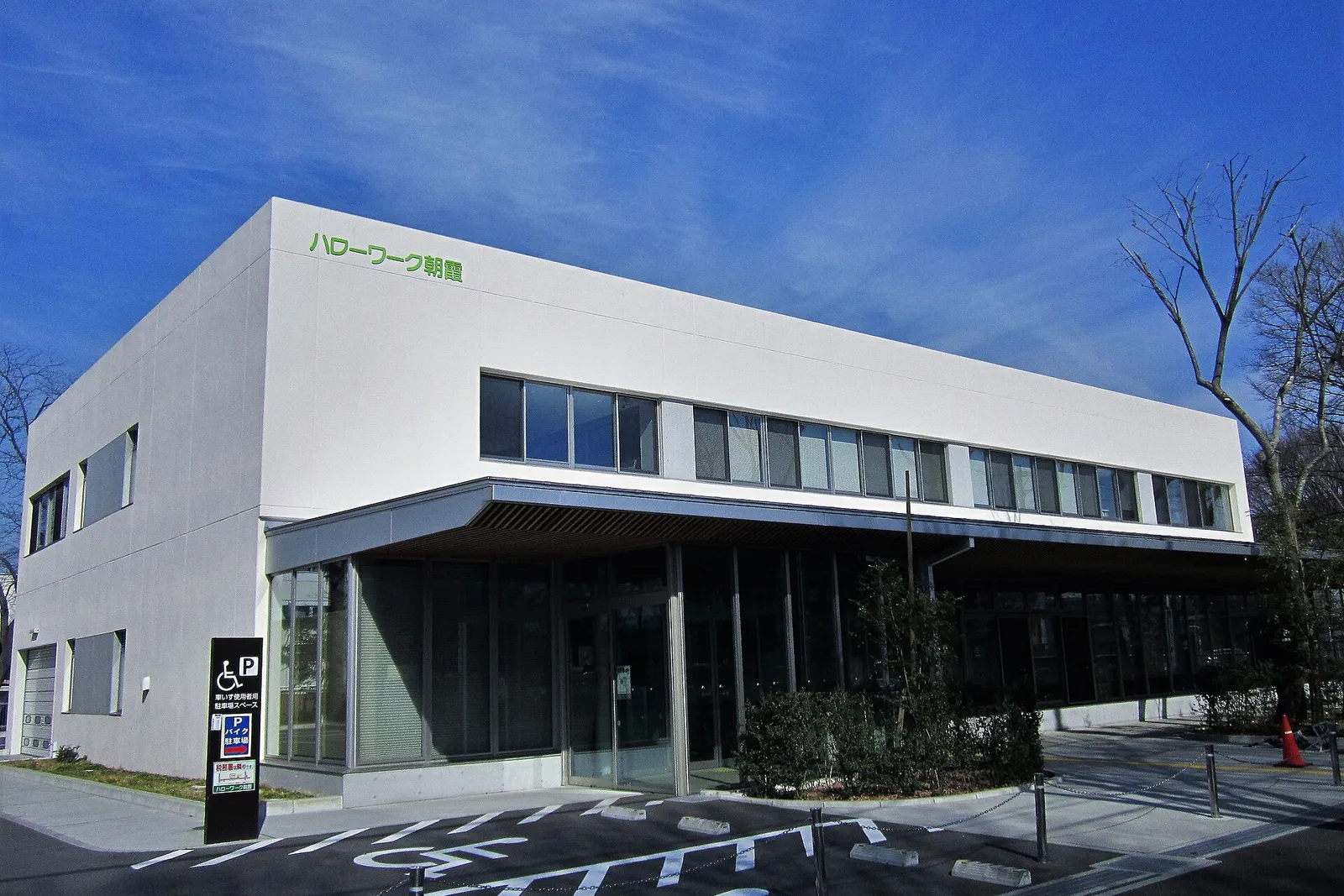 The two-storey Hello Work Asaka public employment office building with large windows under a blue sky in Saitama