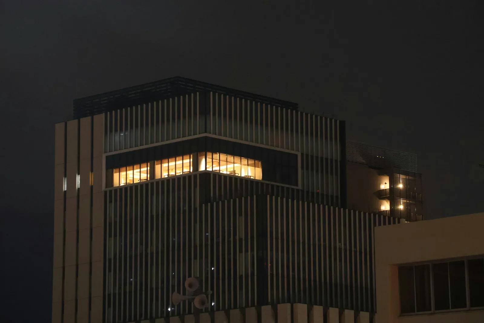 An office building at night with one floor of windows still lit