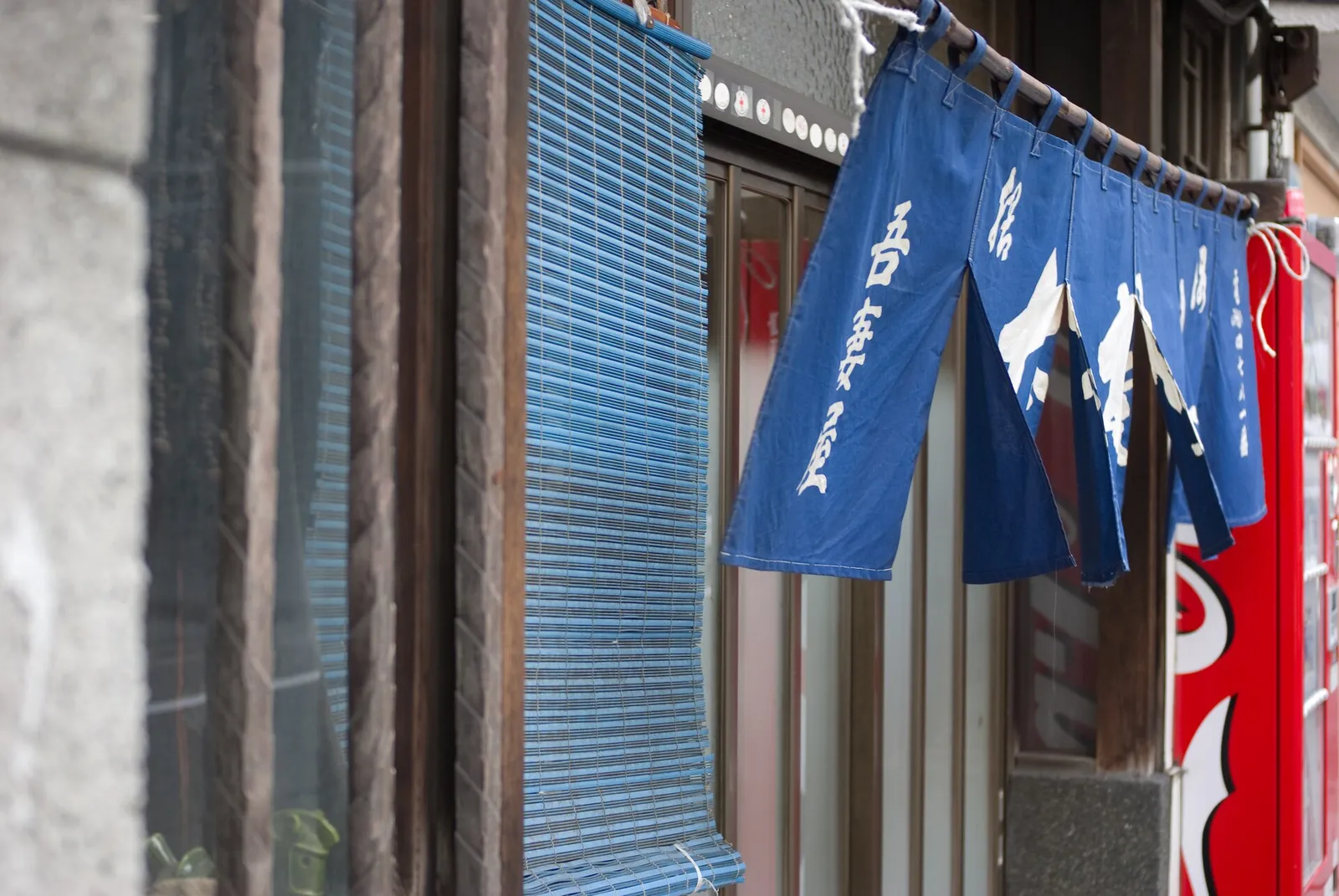 A blue noren curtain with white Japanese lettering hanging at the entrance of a soba restaurant